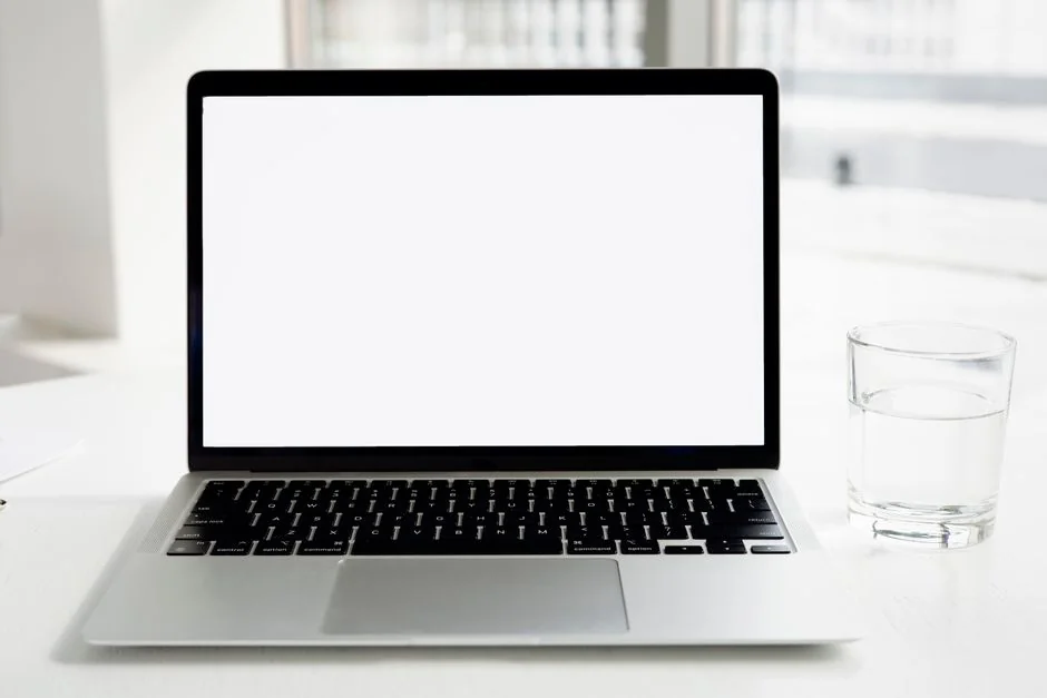 Crop of an anonymous man browsing photos online on a netbook while drinking coffee at a table